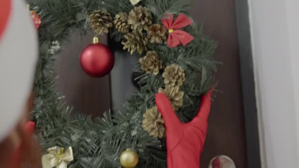 Μια Γυναίκα Κόκκινα Γάντια Κουβαλάει Ένα Χριστουγεννιάτικο Στεφάνι Και Κρεμάει — Αρχείο Βίντεο