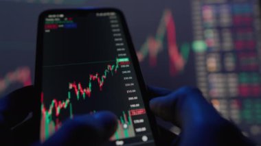 The smartphone screen displays graphs illustrating the movement of stocks in the financial market. Data analysis to predict and predict economic growth or recession and financial crisis or development