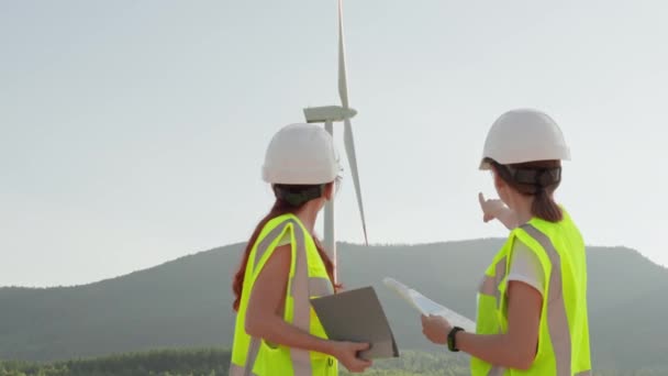 女工程师小组确认风能作为环境友好型能源的重要性 戴着头盔 眼镜和撞灯信号果冻的妇女手里拿着文件 — 图库视频影像