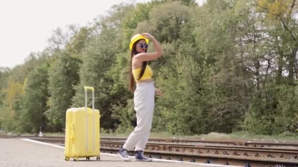 一个有着温馨回忆和夏天梦想的手提箱 一个年轻的女人站在火车站的站台上 沉溺在对冒险和浪漫漫步的平静的期待中 一个女孩在车站等火车 — 图库视频影像