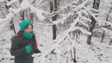 Kış barışı ve mutluluk: Karla kaplı bir ormanda yürüyen genç bir kadın festival sezonunun neşesini hisseder. Ağaç dallarında kar var. Kış atmosferi duyguları bastırır. Erkek