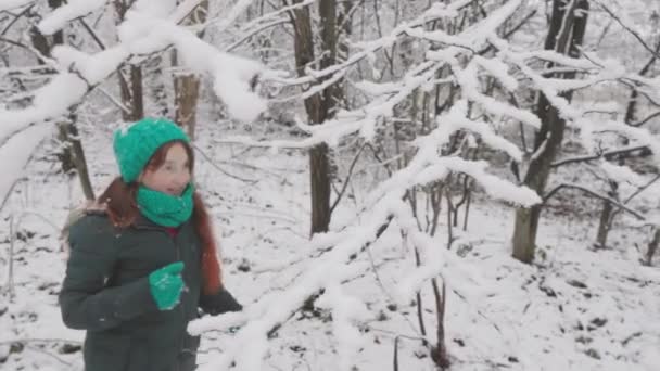 冬天的和平与幸福 一个年轻的女人走在白雪覆盖的森林里 感受着节日的喜悦 雪落在树枝上 冬天的气氛压倒了感情 — 图库视频影像
