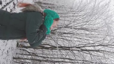 Noel 'in büyüsü, karlı bir ormanda kış yürüyüşlerinden hoşlanan bir kadınla devam eder. Kışın karla kaplı muhteşem bir ormanda bir adamın dikey videosu. Resimli doğa ve kışın güzelliği