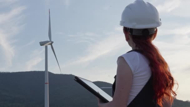 录像展示了一名工程师的工作 他分析和监测风力涡轮机的运行 确保不间断地生产环境友好型电力 妇女在工作 — 图库视频影像