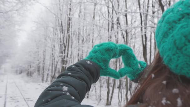 节日的气氛拥抱了一个在雪地的森林里散步并享受寒假的女孩 一个女人爱上了冬天 爱上了美丽的冰雪覆盖的大自然 以心的形状示爱 — 图库视频影像
