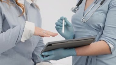 İyileşmek için önemli adımlar: Doktor hastayla birlikte resepsiyonda, en iyi sonuçlar için teşhis ve tedavi planını dikkatle tartışıyor. Doktor tabletteki verileri gösteriyor.