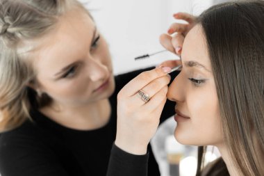 Fotoğraf, güzellik salonundaki bir makyaj sanatçısının müşterilerin kaşlarına ufak estetik düzeltmeler yaptığı anın enerjisini ve sıcaklığını aktarıyor. Tüm bunlar benzersiz bir görüntü yaratmak için.