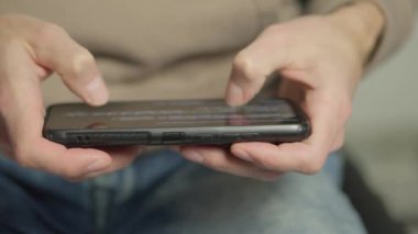 Akıllı telefon kullanan bir adam, fotoğraflara ve haberlere bakar, çevrimiçi dünyaya bir pencere açar. Teknoloji iş başında: akıllı telefonun arka planına karşı gelen bir el kaydırmayı gerçekleştirir,