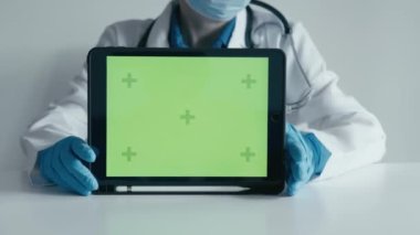 Yeşil ekran. Hekim, terapist, pediyatrist, internet üzerinden hastalarına destek sağlayarak uzaktan çalışmak için elektronik tablet kullandığını gösteriyor. Tıptaki Chromakey.