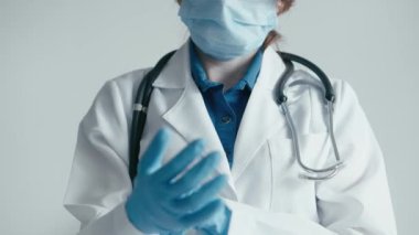 Koruyucu eldivenler ve steteskop giymiş bir sağlık çalışanının portresi sağlık ve güvenin sembolüdür. Doktor kerevitlere koruyucu eldiven takar ve düzeltir. Klinik