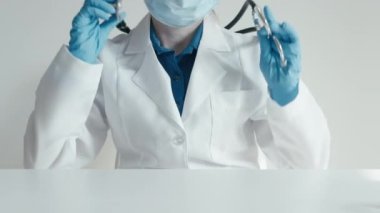 Doktor steteskopu omuzlarından çıkardı ve önündeki masanın üzerine koydu. Bir sağlık çalışanı, klinikte geçirdiği bir günün ardından koruyucu maskeyi çıkarır ve...