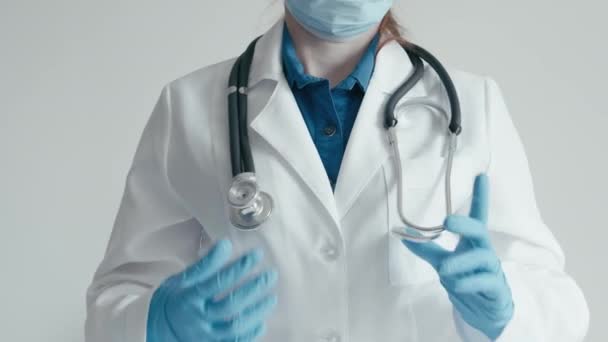 医師は医療機関にいて 医療を提供する準備ができています 白いコートを着た医師と 眼鏡付きのマスクは 医療相談を提供する準備ができています 彼の前に手を伸ばして — ストック動画