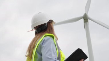 Türbinin yanında dijital tabletle önde gelen bilim adamları: alternatif enerji kaynaklarını araştırıyor. Verimli gelişme: Bir kadın mühendis yeşil enerji sağlamak için bir tablet üzerinde rüzgar jeneratörlerini analiz ediyor