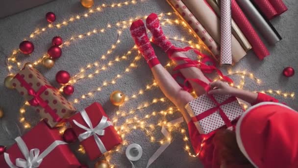 节日装饰的女巫师 一个身穿红色衣服 拿着玩具和礼物的女人 创造了一种充满欢乐和惊喜的圣诞气氛 有节日气息的针锋相对的女人 有圣诞树嘴的女人 — 图库视频影像