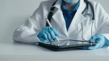 Bir tablet üzerinde hasta bilgilerini incelemeye odaklanan bir tıp uzmanı tedaviye bireysel bir yaklaşım geliştirir. Bir doktor tıbbi verileri girerken bir stil kullanır.