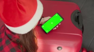 Bayram havası, Noel hediyelerini karıştıran ve Noel tatili ve Yeni Yıl tatili hazırlığı için bir çevrimiçi mağazada cep telefonuyla hediye sipariş veren bir kadını kucaklıyor.