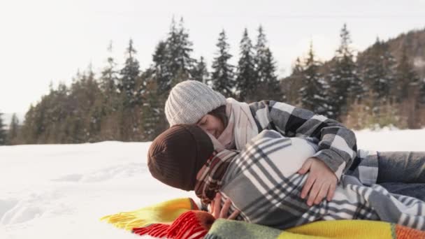 当新婚夫妇在毛毯上花时间时 积雪覆盖的风景增加了放松和欢乐的气氛 温文尔雅和欢乐使一对夫妇在毛毯上分离 他们更喜欢户外娱乐活动 — 图库视频影像