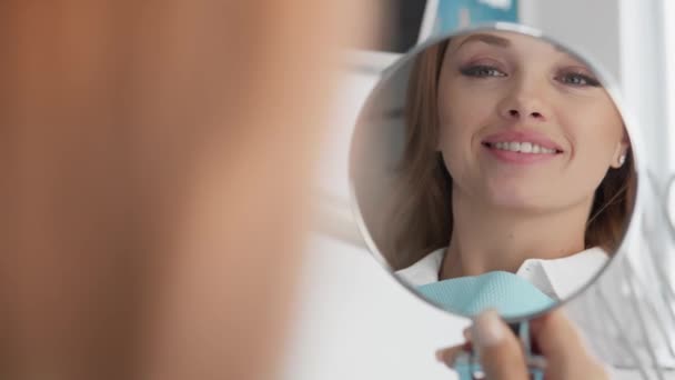 鏡では 歯医者を訪問した後 歯の状態の明確な改善を見ることができます 女性は彼女の素晴らしい笑顔のために複合体なしで笑顔ができることを嬉しく思います — ストック動画