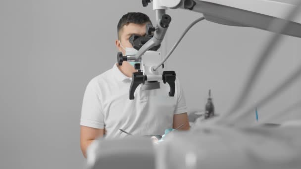 顕微鏡の下で 歯科医は患者歯を慎重に診断し治療する 歯科診療所の医療機器や機器は 手順の正確性と安全性を確保します モダンスタイル — ストック動画