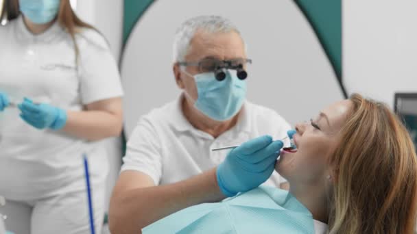 歯科クリニックの治療プロセスは 高水準の医療を示しています 歯科医とアシスタントは 損傷した歯を復元するために緊密に取り組んでいます 高品質の4K映像 — ストック動画