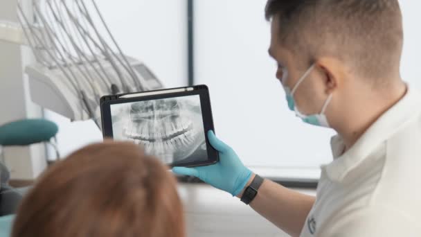 Dentysta Przedstawia Wyniki Tomografii Panoramicznej Zębów Pacjenta Tablecie Pacjentka Otrzymuje — Wideo stockowe