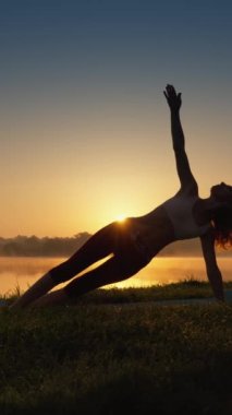 Doğayla Uyum içindeki Yoga: Sağlıklı Yaşam Tarzının Sırları. Bir kadın, meditasyonu yoga uygulamasına doğal bir ortamda dahil eder. Güneşin doğuşundaki bir adamın silueti, egzersiz ve spor