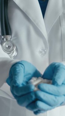 Bir tıp uzmanı avuçlarında ilaç olan bir sürü beyaz kapsül tutar. Vitaminli haplar ve sağlık için besin takviyeleri. İlaçların içindeki doğal malzemeler tabletlerde. Mavi giyiyordu.