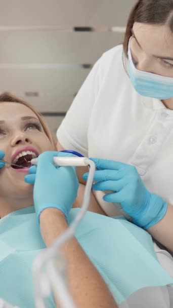 患者は痛みを和らげ 彼女の快適さに対する思いやりのあるアプローチを感じます 歯科医師とアシスタントは 歯科オフィスで安全で高品質の歯科ケアを提供しています 高品質の4K映像 — ストック動画