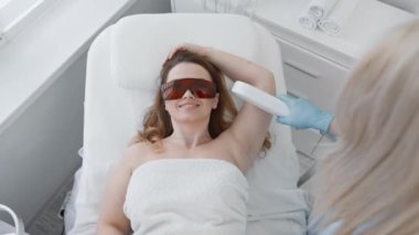 Güzellik kliniğindeki güzellik uzmanları lazerle saç aldırıyor. Derinin pürüzsüz olmasını ve işlemden zevk almasını garanti ediyor. Fotokopi çeken bir kadın kendini güvende ve sakin hisseder.