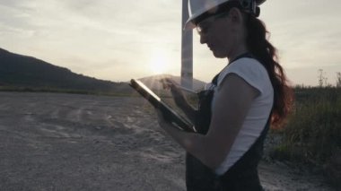 Video, bir rüzgar türbininin işleyişini araştıran, enerji kapasitesini analiz eden ve yeşil elektrik üretimi için veri toplayan bir mühendisi gösteriyor. Yel değirmeninde çalışan kadın bilim adamı