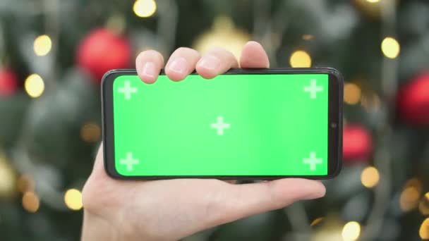 Sebuah Tangan Dengan Smartphone Dekat Pohon Natal Sebagai Simbol Liburan — Stok Video
