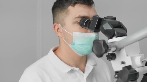 Ένας Οδοντίατρος Εκτελεί Σιγουριά Μια Χειρουργική Επέμβαση Χρησιμοποιώντας Ένα Μικροσκόπιο — Αρχείο Βίντεο
