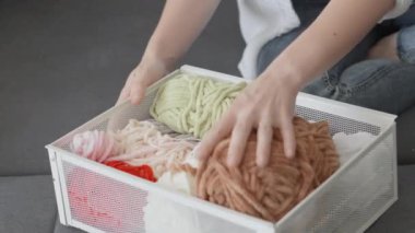 Bir kadın gelecekteki arigurumi örgü örmek için evinin önüne bir çekmece iplik koyuyor. Rahatlayın ve evinizde dinlenin. Yüksek kalite 4k görüntü