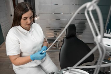 Bir diş hekimi klinikte diş beyazlatma ve düzeltme işlemleri yapmaya hazırlanır. Bir dişçi, bir tıp merkezindeki hastalar için diş implantı hazırlar. Yüksek kalite fotoğraf