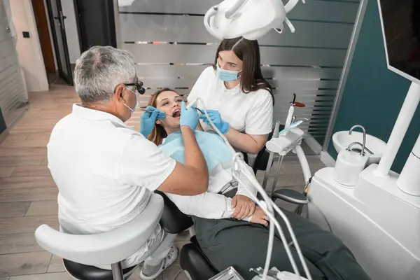 The procedure for installing dental implants is performed with maximum comfort for the patient. A dentist uses modern techniques to treat and restore dental health with a dental assistant. High