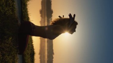 Bir kadın doğal bir ortamda esneklik ve zarafetle asanas gösterisi yapar. Yoga, açık havada fiziksel ve zihinsel potansiyelin gelişmesi için. namaste 'nin güzel bir gündoğumundaki dikey videosu