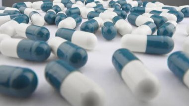 Doğal malzemelerden üretilen vitaminli kapsüller, sağlığı korumanın tek yoludur. Beyazlı mavi kapsüller. İlaç üretimi ve satışı. Daire şeklinde hareket edin ve hapları yakın plan yapın. Yüksek