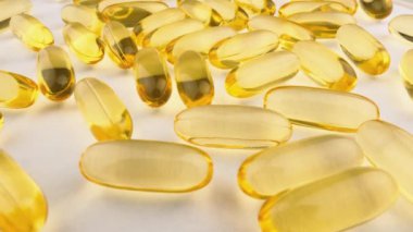 Yakın plan: beyaz arkaplandaki kapsüllerdeki vitaminler ve besin takviyeleri. Sarı ve altın balık yağı kapsülleri sağlık için bir besin takviyesidir. Omega 3, 6 ve 9 yağ asitli kapsüller. Yüksek