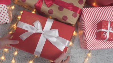 Bir kadın Noel ağacının altından bir hediye alır ve bir paket alır. Yeni yılın atmosferi ve sürprizler. Hediye değiş tokuşuna hazırlanıyorum. Bir sürpriz bekliyorum. Yüksek kalite 4k