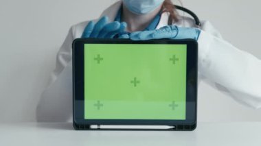 Doktor, hastalara önemli bilgilere, kişisel sanal ofise ve internete hızlı erişim imkanı sağlayan, tıbbi hizmetler için reklamı olan yeşil bir tablet ekranı gösteriyor.