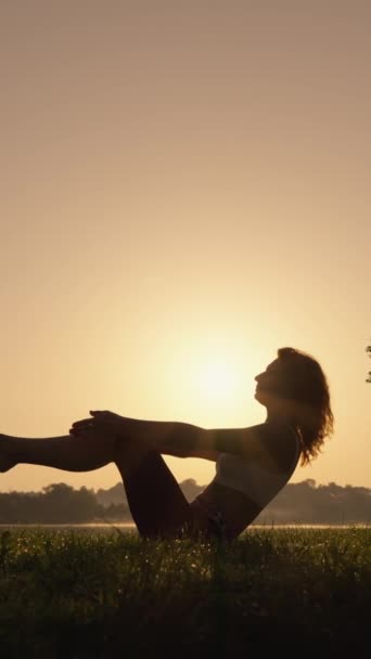 湖の近くの日の出で新鮮な朝の空気の中で呼吸する女性は 身体と精神の調和とリラックスのためにヨガを紹介し 実行します アサナを演奏する女性の垂直ビデオ Aにチューニング — ストック動画