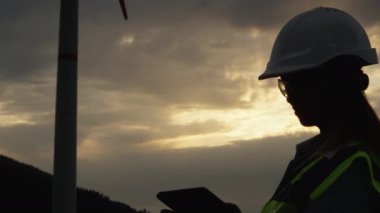Yel değirmeni tabletli mühendis: rüzgar enerjisi üzerine bilimsel araştırma. Türbinin yanında dijital tableti olan bir bilim adamı: sürdürülebilir bir rüzgar jeneratörü sisteminin geliştirilmesi için bir rehber. Yüksek kalite 4k