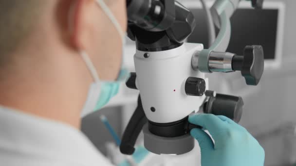 의사는 진료소 근접에서 현미경으로 환자의 치아를 수술합니다 진료소에서 의사는 현대적인 — 비디오