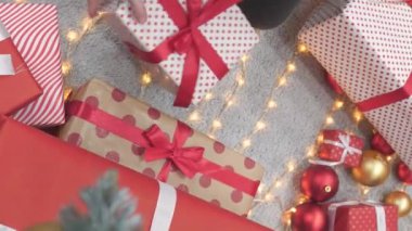 Noel tatili için renkli hediyeleri paketleyen neşeli bir kadın elinde çeşitli kağıtlara sarılı ve çevre dostu malzemelerden yapılmış parlak bir kutu var. Yüksek kalite 4k görüntü