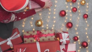 Sıcak ve rahat bir evde, genç bir kadın Noel kutlamaları için hediyeler hazırlıyor. O rahat bir kazak giydi ve hediyeleri renkli kutulara dikkatlice sardı. Her hediye özel bir semboldür.