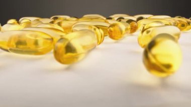 Beyaz arka planda vitaminli şeffaf kapsüller ve yağ asitleri. İlaç üretimi. Sağlık için sarı kapsüllerdeki balık yağı. Omega 3. Yüksek kalite 4k görüntü
