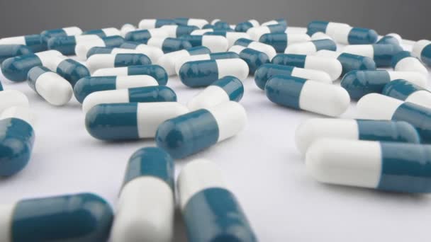 Leki Niebiesko Białe Kapsułki Obracają Się Białym Szarym Tle Zbliżenie — Wideo stockowe