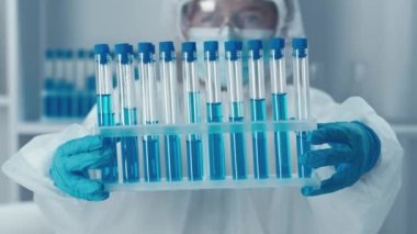 Kimya laboratuvarında bir bilim adamı. Videoda genetik araştırmalar, DNA teknolojisinin kullanımı ve insan sağlığını iyileştirmek için yeni ilaçların geliştirilmesi üzerinde duruluyor. Aşı geliştirme süreci