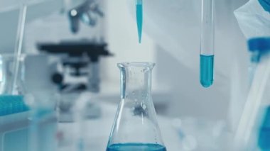 Boru, çözeltiyi bir şeker kutusuyla test tüpüne çeker. Video, tıbbi ve bilimsel alanda birlikte çalışan farklı uzmanlardan bilim adamlarının günlük iş akışını gösteriyor.