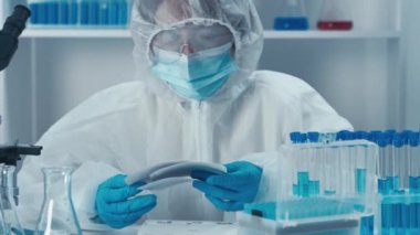 Video, salgınla mücadelede teknolojinin rolünü, yeni testler geliştirmekten hastalıkları tedavi etmek için etkili ilaçlar üretmeye kadar inceliyor. Bir kimyager laboratuvar testlerinin sonuçlarını kontrol eder.